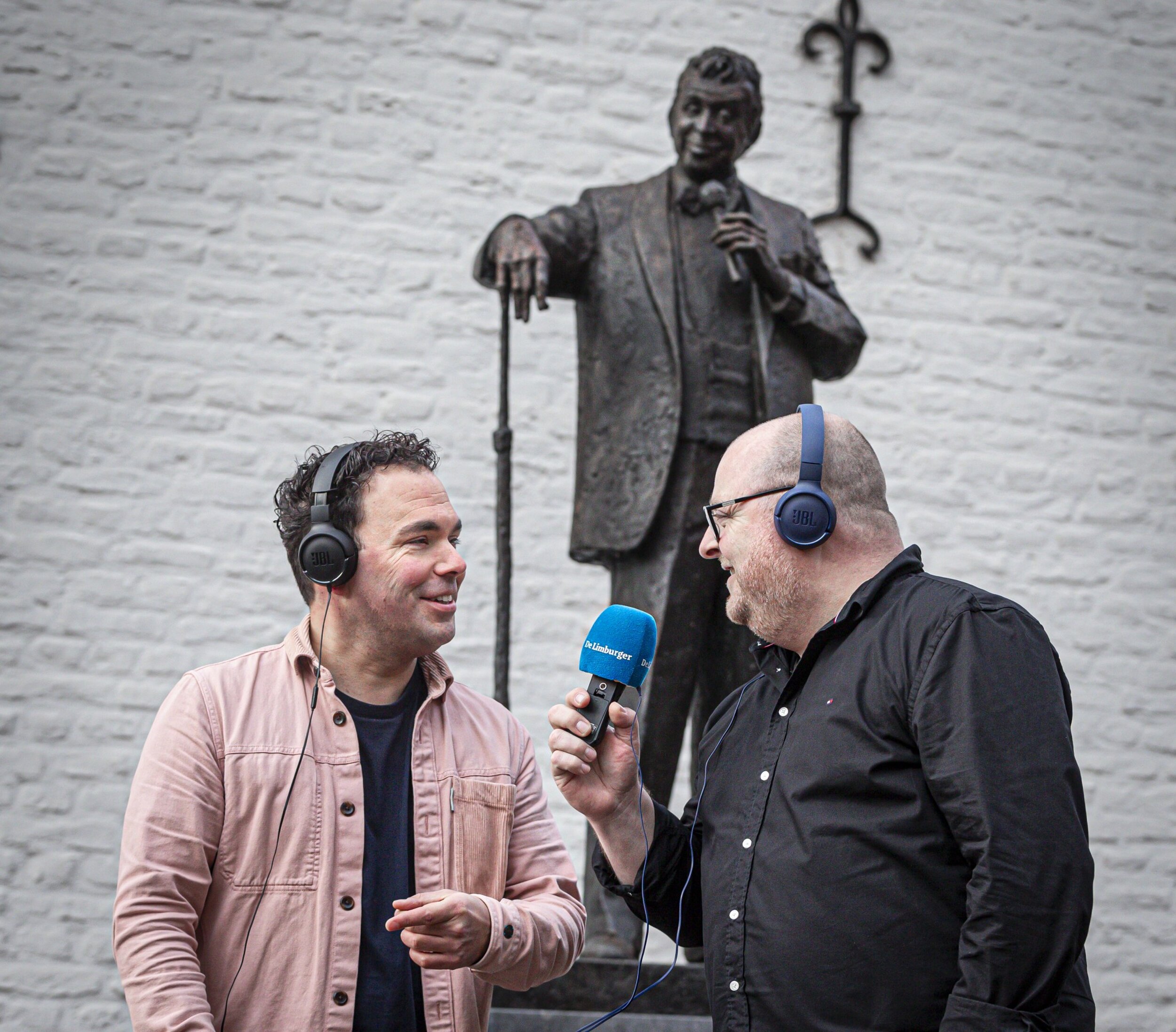 Paul Dolhain (met bril) en Nick Bruls, beiden verslaggever van Dagblad De Limburger, staan bij het standbeeld van Toon Hermans in Sittard. Foto: Roger Dohmen